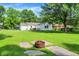 A backyard features a fire pit, lush green lawn and a home with light yellow siding at 7600 S Oak Dr, Indianapolis, IN 46227