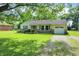Traditional single-story home featuring an attached garage, stone accents, and a lush green yard with mature trees at 7600 S Oak Dr, Indianapolis, IN 46227