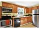 The kitchen features stainless steel appliances, black dishwasher, wooden cabinetry, double sink and natural light at 7600 S Oak Dr, Indianapolis, IN 46227
