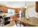 A well-lit kitchen features warm wood cabinetry, stainless steel appliances, and a stone-style countertop breakfast bar at 7600 S Oak Dr, Indianapolis, IN 46227