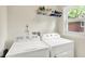 Bright laundry room with white appliances, a window, and storage space above at 7600 S Oak Dr, Indianapolis, IN 46227