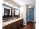 Bathroom featuring double sinks, wood-look accent wall, and shower at 7686 Micawber Ct, Indianapolis, IN 46256