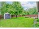 Large backyard with green lawn, deck, wooden fence, and convenient storage shed at 7918 Bitternut Dr, Indianapolis, IN 46236