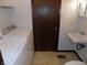 A well-lit bathroom featuring a toilet, sink, and washing machine at 8609 Stonewall Dr, Indianapolis, IN 46231