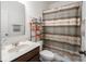 Well-lit bathroom featuring a sink, toilet, and bathtub with shower curtain, plus useful shelving at 9001 Fitzgerald Dr, Indianapolis, IN 46239