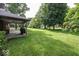Expansive backyard with a covered patio, lush lawn, mature trees, and ample space at 9133 Log Run N Dr, Indianapolis, IN 46234