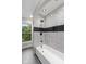 Elegant bathroom featuring a bathtub with a shower, neutral tile, and natural light at 9148 Oak Knoll Ln, Fishers, IN 46037