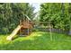 Backyard features a wooden playset with a slide and swings surrounded by green grass and mature trees at 10717 Windermere Blvd, Fishers, IN 46037