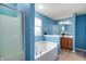 Bright blue bathroom featuring a garden tub, shower, vanity, and decorative plants at 1143 Hampton Dr, Greenwood, IN 46143