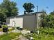 View of a large outbuilding with sliding doors and a small service door, surrounded by overgrown foliage at 1170 E 400 S, Lebanon, IN 46052