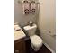 Close-up of a toilet in a bathroom with light grey walls, a wooden cabinet and patterned towels at 12328 Quarry Face Ct, Fishers, IN 46037