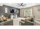 Living room with a large TV, two grey sofas, hardwood floors, a ceiling fan, and ample natural light at 126 Winding Brook Way, Pendleton, IN 46064