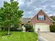 Charming brick home featuring a lush green lawn, mature trees, and a two-car garage, creating a welcoming curb appeal at 12656 Cerromar Ct, Carmel, IN 46033