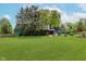 Expansive green backyard featuring multiple patios and a two-story building with wood and green horizontal siding at 1810 S Raceway Rd, Indianapolis, IN 46231