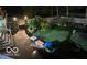 Nighttime view of a backyard featuring stone accents, a patio with a grill, and lush greenery illuminated by soft lighting at 1810 S Raceway Rd, Indianapolis, IN 46231