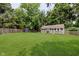 Spacious backyard featuring well-maintained green grass, two sheds, and a privacy fence surrounded by mature trees at 1810 S Raceway Rd, Indianapolis, IN 46231