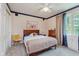 Bright bedroom featuring a ceiling fan, large window, and neutral-colored walls, complemented by a wooden headboard bed at 1810 S Raceway Rd, Indianapolis, IN 46231