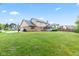 Sprawling backyard with lush green lawn, mature trees, and a traditional two-story home at 1826 Spruce Dr, Carmel, IN 46033