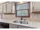 Close-up of kitchen sink with granite countertops, tiled backsplash, and a window view at 1826 Spruce Dr, Carmel, IN 46033