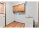 Well-lit laundry room with wood-look floors, upper cabinets and utility sink at 1826 Spruce Dr, Carmel, IN 46033