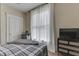 Bright bedroom featuring a gray plaid bed, sheer curtains, and a dark wood dresser with natural lighting at 250 N Home Ave, Franklin, IN 46131