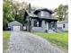 View of the gray home with a detached garage and gravel driveway at 2720 S Taft Ave, Indianapolis, IN 46241