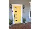 Modern yellow front door with decorative windows, flanked by potted plants and stylish sconces at 302 Penn St, Westfield, IN 46074