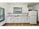 Efficient kitchen featuring white cabinets, laminate countertops, stainless steel sink, and ample natural light at 3028 Hovey St, Indianapolis, IN 46218