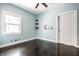 Bedroom featuring dark hardwood floors, blue walls, and a window at 33 N Webster Ave, Indianapolis, IN 46219