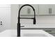 Close-up of a kitchen sink with a matte black faucet and white countertops with matching cabinets at 3365 Riverside Dr, Columbus, IN 47203