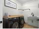 Modern laundry room features black front-load machines, wood countertop, light green cabinets, and black hardware at 3365 Riverside Dr, Columbus, IN 47203