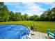 An above-ground pool with a ladder and pump sits next to a wooden deck in a large, grassy backyard at 379 N Marion St, Morgantown, IN 46160