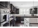 Modern kitchen with dark wood cabinets, granite counters, stainless steel appliances, and natural light from the window at 4529 Panthera Leo Dr, Carmel, IN 46074