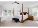 Spacious main bedroom with four-poster bed, tray ceiling, sitting area and large windows at 4529 Panthera Leo Dr, Carmel, IN 46074