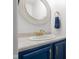 Elegant bathroom featuring navy blue vanity, gold hardware, and decorative round mirror at 4605 Clairmont Dr, Columbus, IN 47203