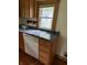 Kitchen area with dishwasher, wood cabinets, and dark countertops at 4931 Orion Ave, Indianapolis, IN 46201
