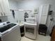 Bright laundry room with white appliances, cream-colored sink, and white cabinets for storage at 530 Denny Dr, Mooresville, IN 46158