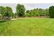 Large green backyard with trees, a wooden fence, and a patio table with an umbrella and chairs at 5456 Reston Dr, Plainfield, IN 46168