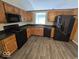 Well-lit kitchen featuring oak cabinets, black appliances, and durable laminate countertops at 5825 Sapelo Dr, Indianapolis, IN 46237