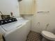 Bright laundry room with a utility sink, cabinet space, a toilet, and a patterned rug at 5941 Deerwood Ct, Indianapolis, IN 46254