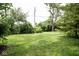 Sprawling backyard featuring green grass, privacy trees, and shade at 6180 Winnpeny Ln, Indianapolis, IN 46220