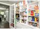 Walk-in pantry features white shelving and door to kitchen with modern, neatly organized food and household items at 6180 Winnpeny Ln, Indianapolis, IN 46220