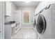 A well-organized laundry room featuring white cabinetry, granite countertops, and modern appliances at 780 Chatham Hills Blvd, Westfield, IN 46074