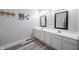 Bathroom features plank flooring, double sinks, white cabinetry, and modern lighting at 8023 Talliho Dr, Indianapolis, IN 46256