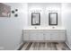 Bright bathroom featuring plank flooring, double sinks, white cabinetry, and modern decor at 8023 Talliho Dr, Indianapolis, IN 46256
