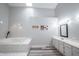 Bathroom features plank flooring, soaking tub, white cabinetry, and modern lighting at 8023 Talliho Dr, Indianapolis, IN 46256
