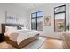 Bright bedroom with large windows, hardwood floors, a gray upholstered headboard and light colored walls at 855 N East N St # 104-B, Indianapolis, IN 46202