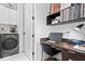 Laundry room with office nook featuring a built-in desk, shelving, and a sleek washer/dryer at 855 N East N St # 104-B, Indianapolis, IN 46202