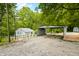 Wide shot showcasing the house and large carport on a gravel driveway, fenced in yard and surrounded by lush trees at 8576 Riser Dr, , IN 46164