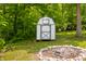 A charming storage shed sits beside a fire pit in a treed yard at 8576 Riser Dr, , IN 46164